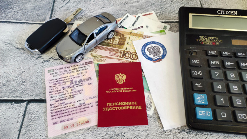 Модель автомобиля, ключи, деньги, документы и калькулятор на столе