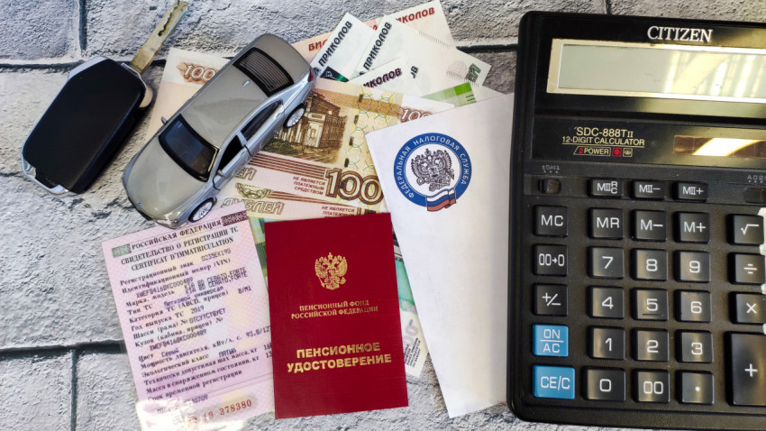 Модель автомобиля, ключи, деньги и документы на машину на столе