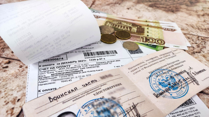 Удостоверение ветерана БД, счет за коммунальные услуги и деньги на столе