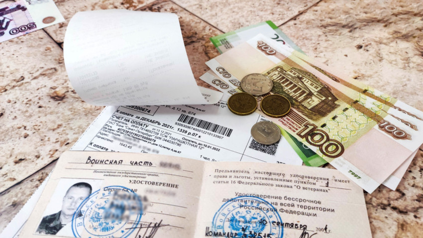 Удостоверение ветерана боевых действий, коммунальный счет и деньги на столе