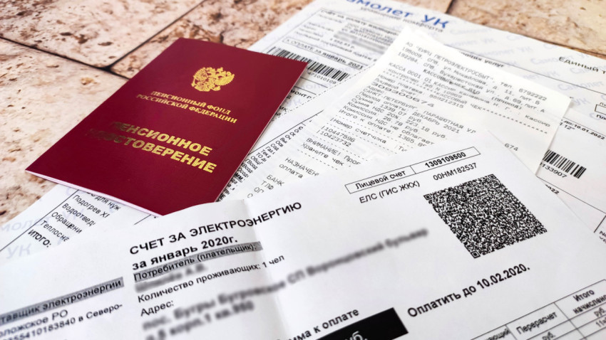 Квитанции за электроэнергию и пенсионное удостоверение на столе