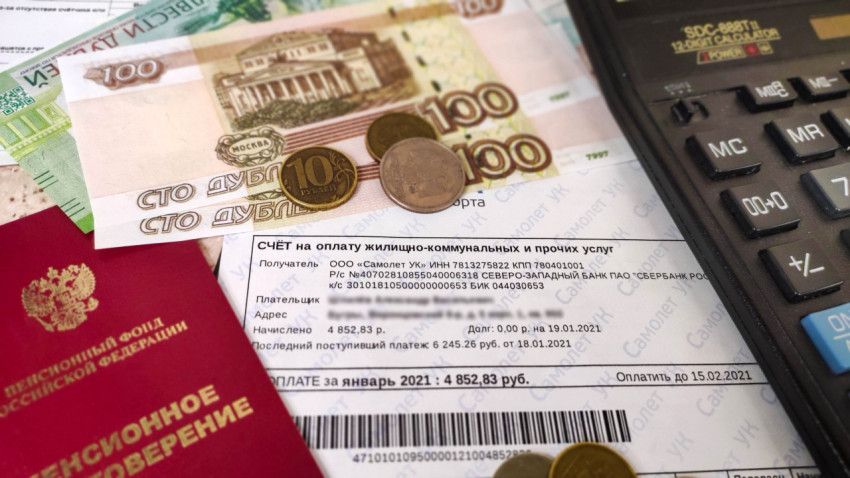 Квитанция за жилищно-коммунальные услуги с пенсионным удостоверением и расчетами на калькуляторе
