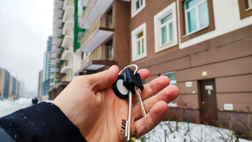 Ключи в руке на фоне многоквартирного дома