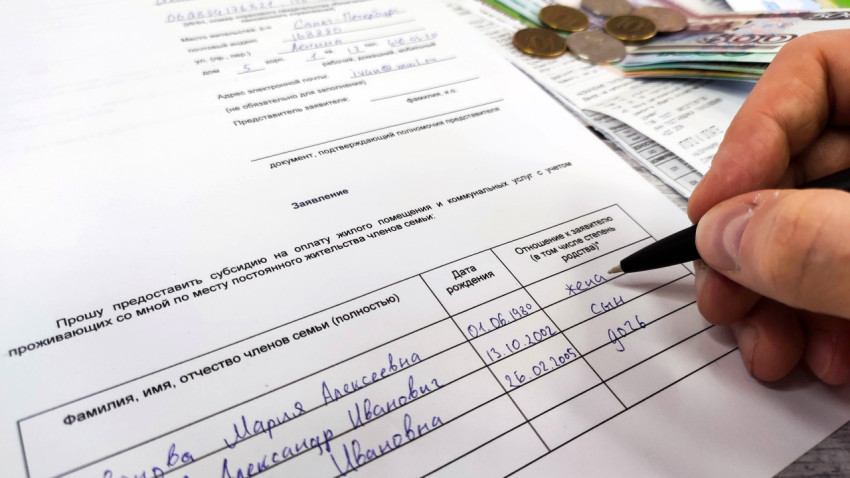 Человек пишет заявление на получение субсидии на оплату ЖКХ