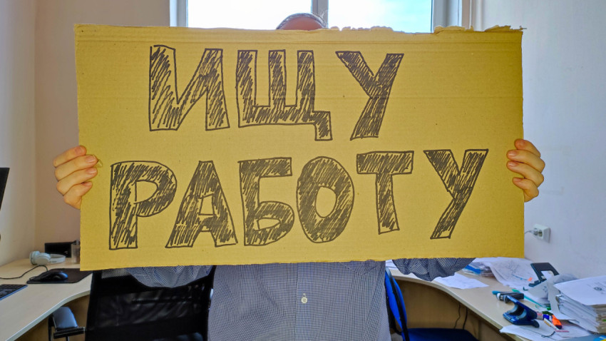 Мужчина с картонной табличкой ищет работу
