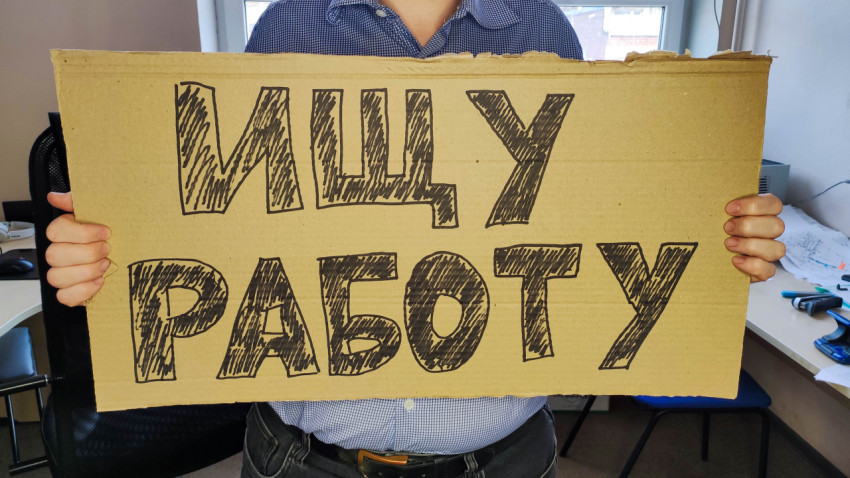 Мужчина ищет работу, держа в руках табличку с надписью «Ищу работу»