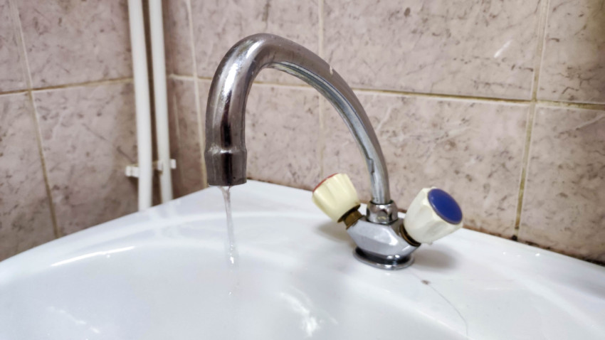 Вода струится из открытого крана на раковине в ванной комнате