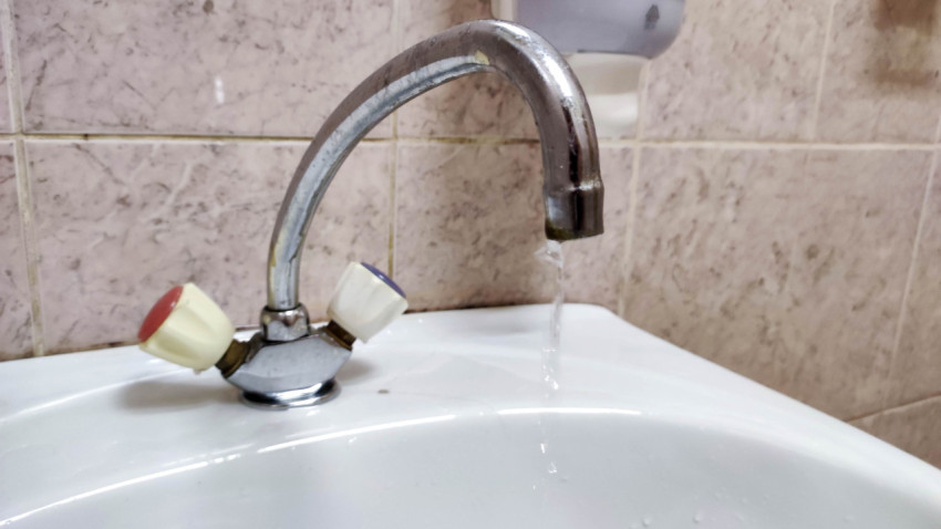 Кран с водой течет в раковине в ванной комнате