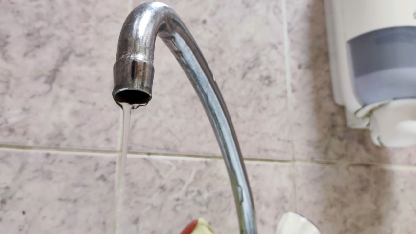 Вода течет из открытого крана в ванной комнате