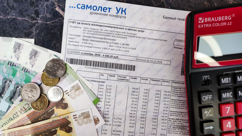 Квитанция об оплате жилищно-коммунальных услуг с деньгами и калькулятором на столе