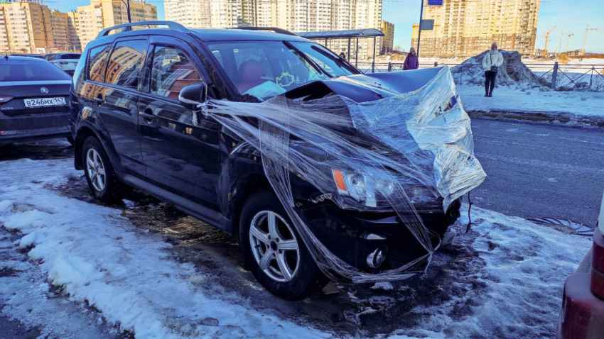 Сломанный автомобиль с поврежденным капотом на обочине дороги в городе