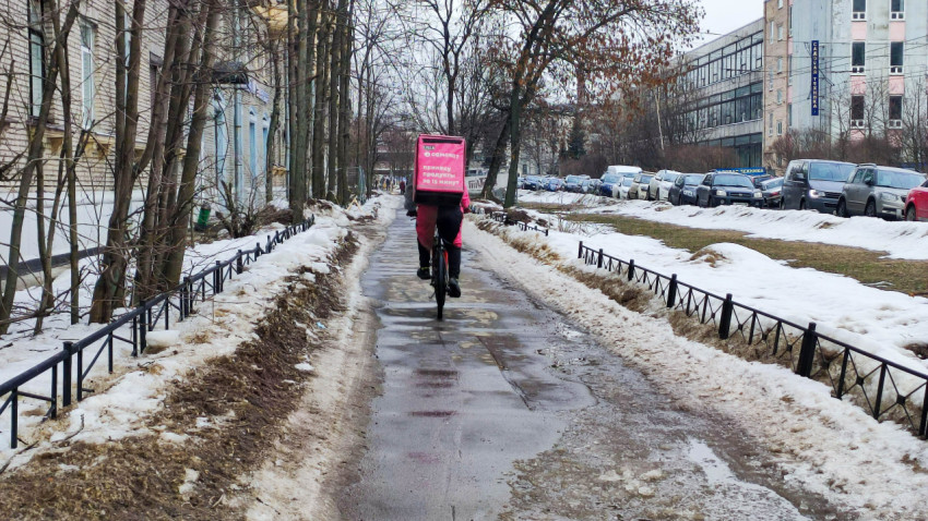 Доставщик на велосипеде едет по зимнему тротуару