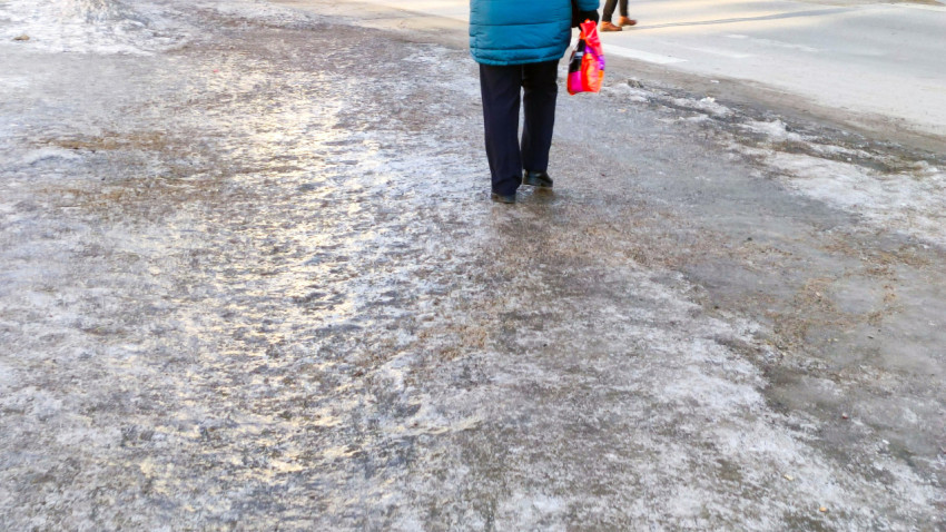 Пешеход проходит по замерзшему тротуару