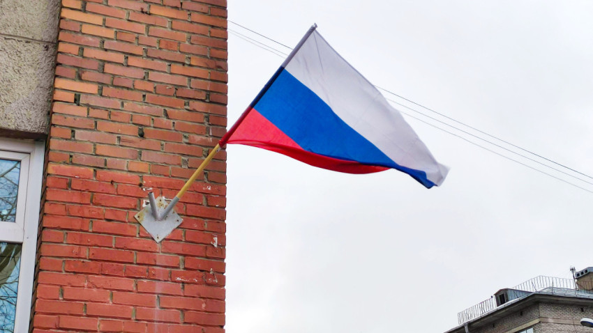 Российский флаг развевается на стене кирпичного здания