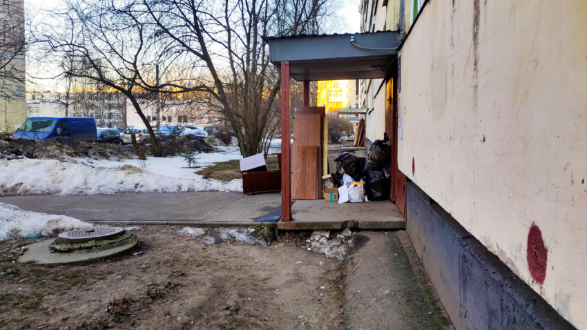 Старая мебель и мусорные мешки у входа в подъезд