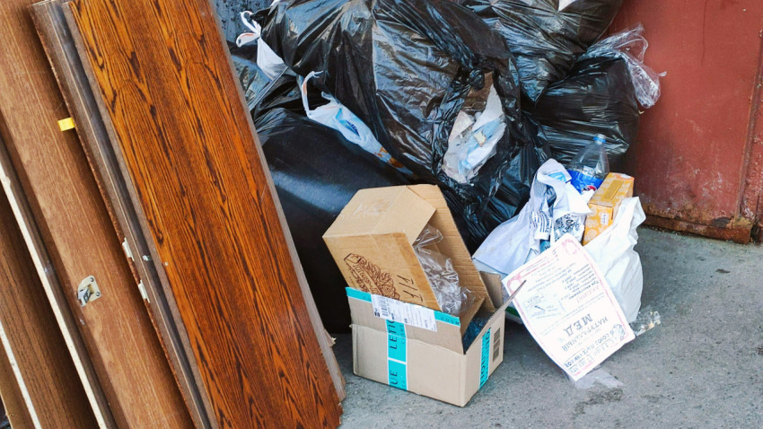 Старая мебель и мусорные пакеты у двери подъезда