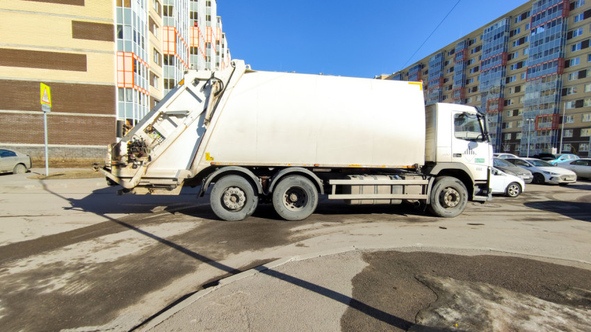 Мусоровоз во дворе многоквартирного дома в городе