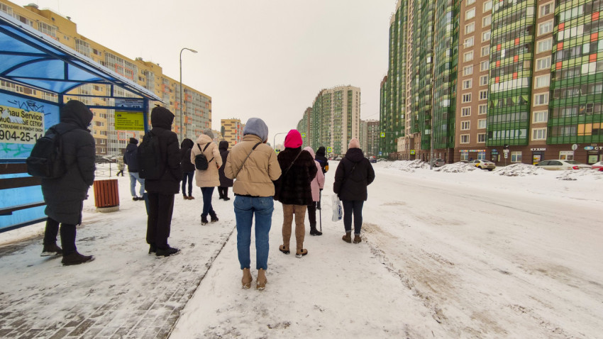 Люди ждут автобус на остановке в снежный день