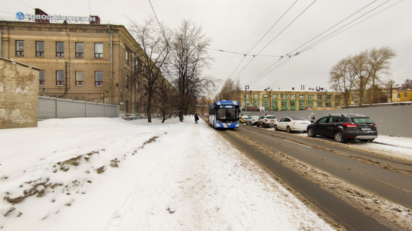 Заснеженный тротуар и троллейбус в зимнем городе