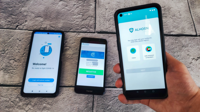 Человек держит смартфон с приложением ALHOSN, два телефона на фоне