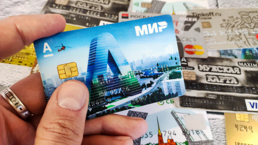 Банковская карта «МИР» в руке на фоне других карт