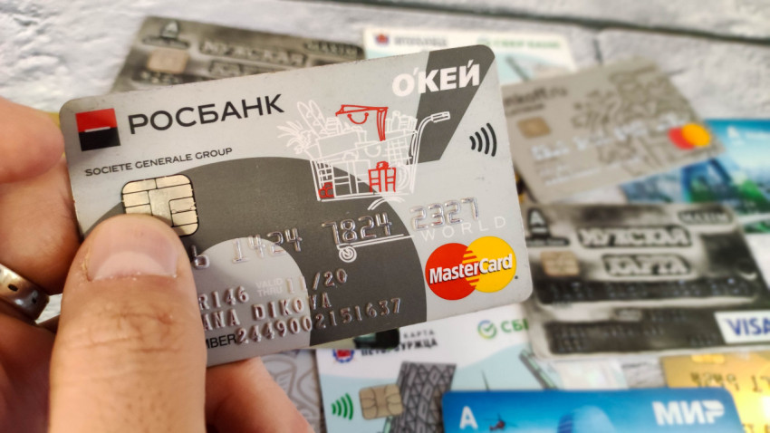 Кредитная карта Росбанка в руке на фоне других платежных карт