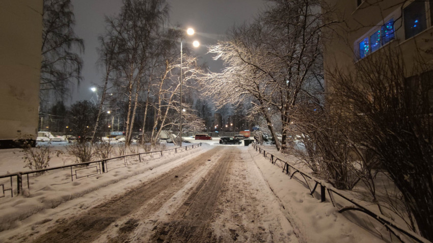 Заснеженная дорога во дворе жилого дома ночью