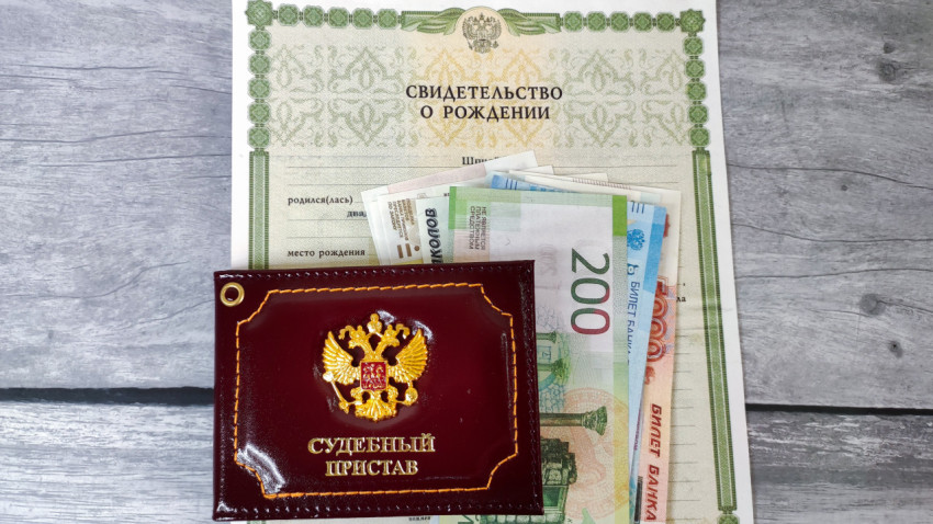 Судебный пристав и деньги на фоне свидетельства о рождении