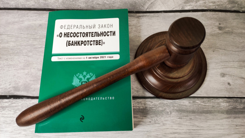 Судейский молоток на фоне закона о банкротстве на деревянной поверхности