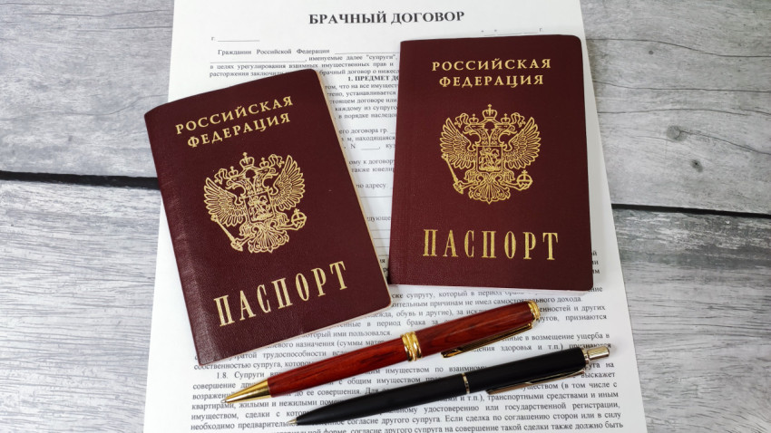 Российские паспорта на фоне брачного договора с авторучками на деревянной поверхности
