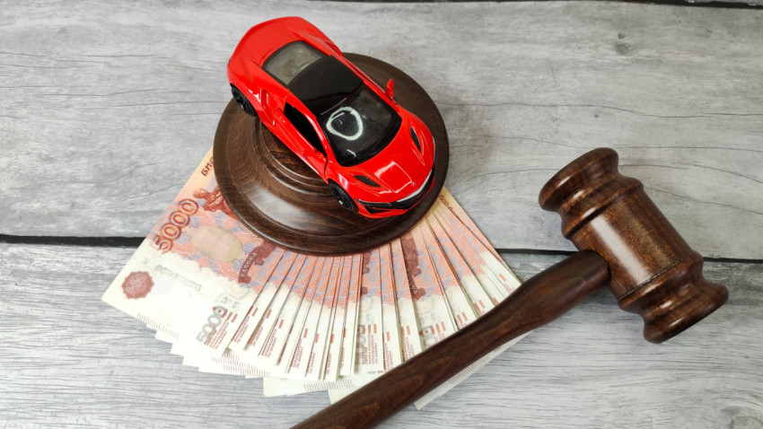 Игрушечный автомобиль на судейском молотке и пачке пятитысячных купюр