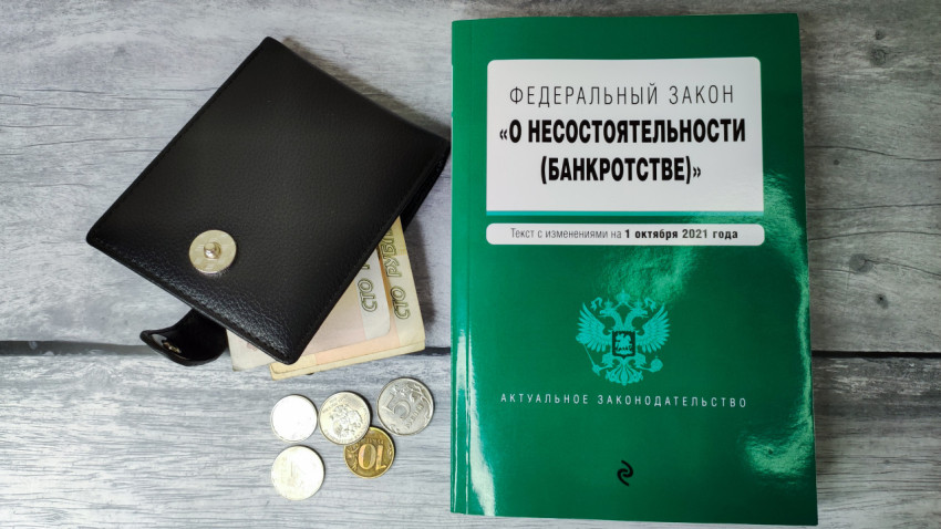 Открытый кошелёк с купюрами и монетами рядом с законом о банкротстве