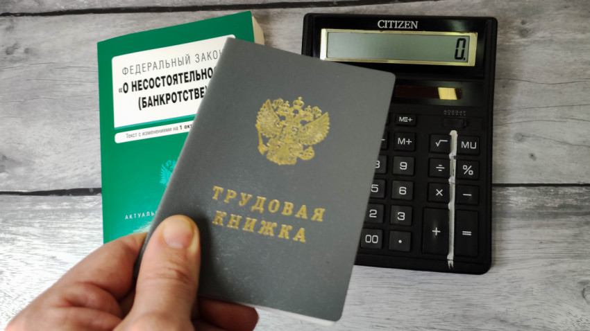 Трудовая книжка на фоне закона о банкротстве и калькулятора