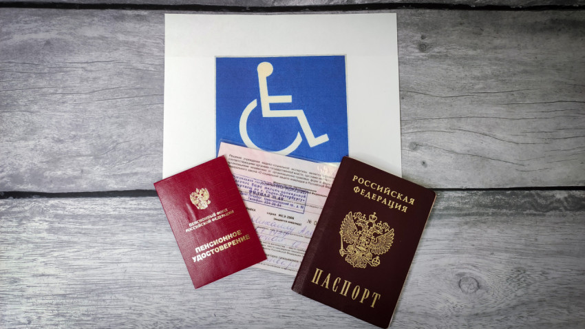 Пенсионное удостоверение и документы инвалида на фоне символа