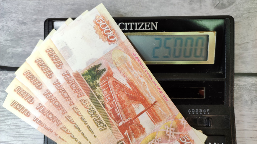 Пять купюр по 5000 рублей на калькуляторе с суммой 25000