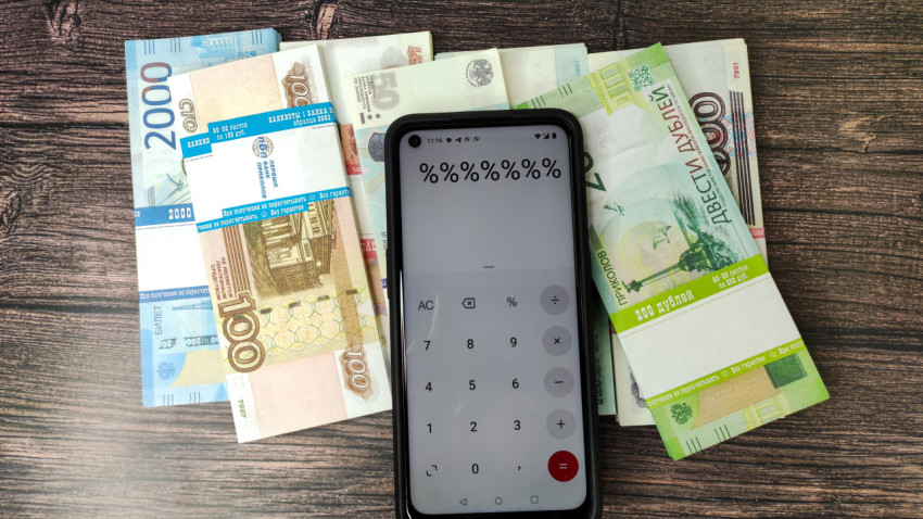 Смартфон с калькулятором и деньги на фоне деревянной поверхности
