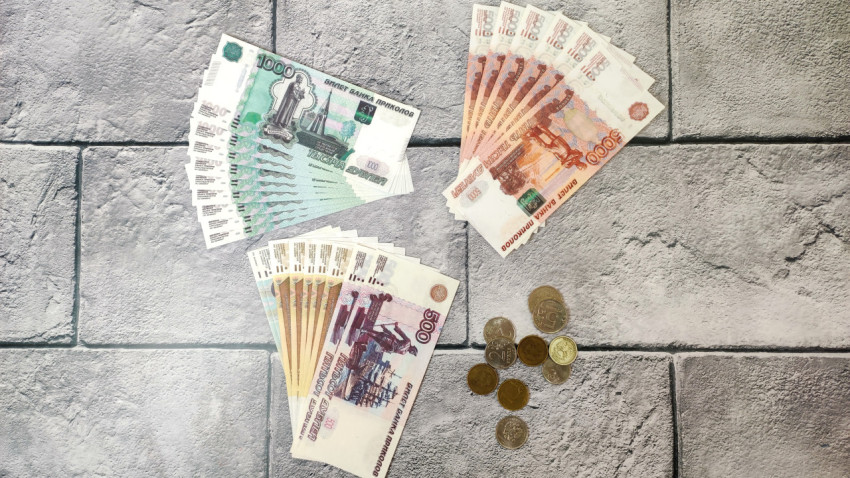 Разложенные купюры и монеты на каменном фоне