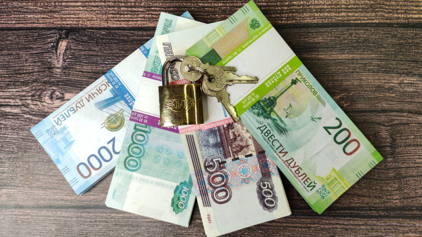Купюры под замком с ключами на деревянной поверхности