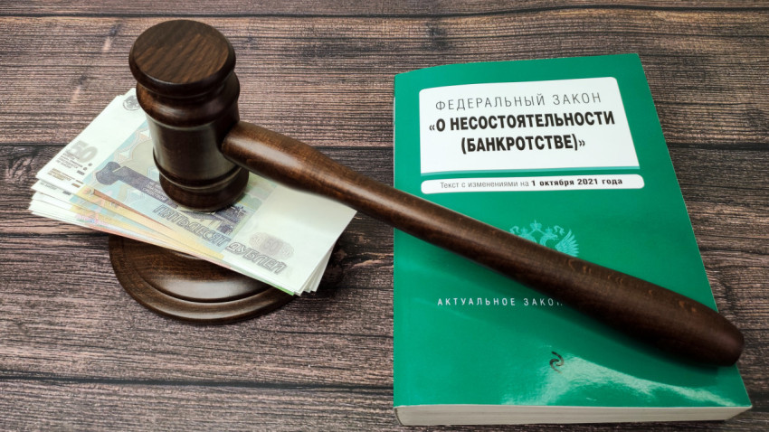 Судейский молоток и деньги рядом с книгой о банкротстве