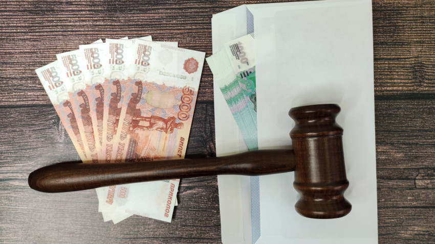 Купюры и конверты под судейским молотком на деревянной поверхности