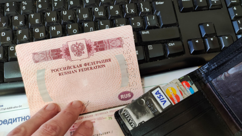 Загранпаспорт и банковские карты на фоне клавиатуры и отчёта