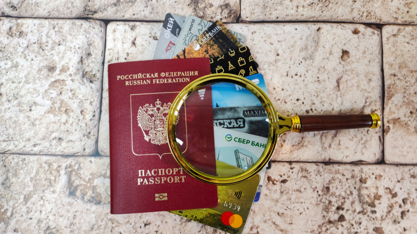Загранпаспорт и банковские карты под лупой на мраморном фоне