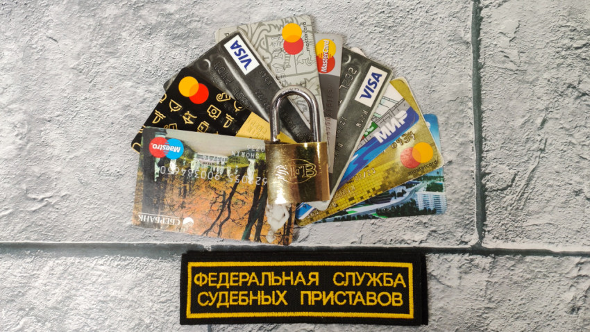 Банковские карты под замком с эмблемой службы приставов
