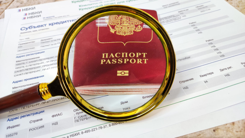 Заграничный паспорт под лупой на фоне кредитного отчета