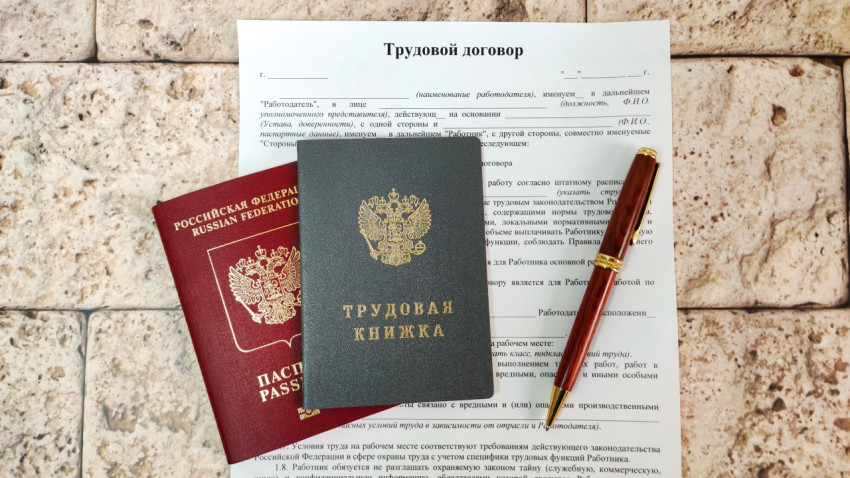 Трудовая книжка и загранпаспорт рядом с подписанным трудовым договором