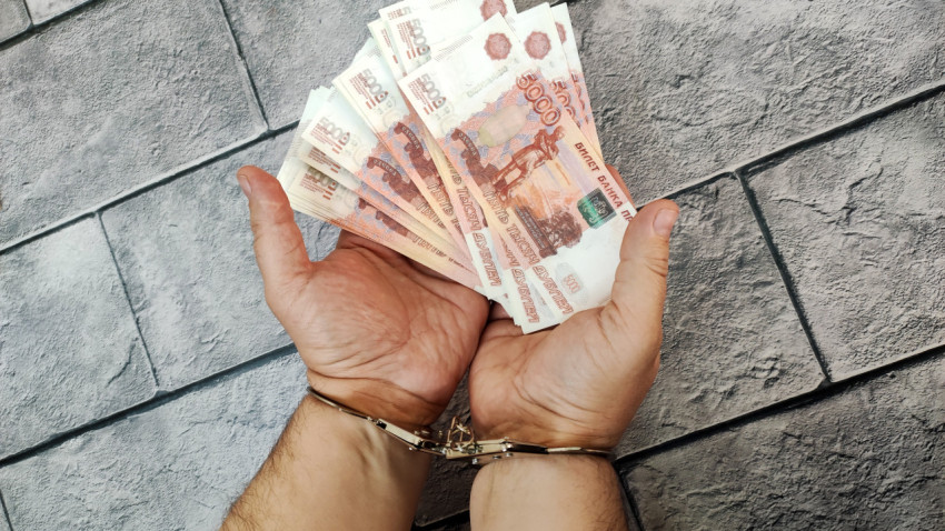 Наручники и пятитысячные купюры в раскрытых ладонях