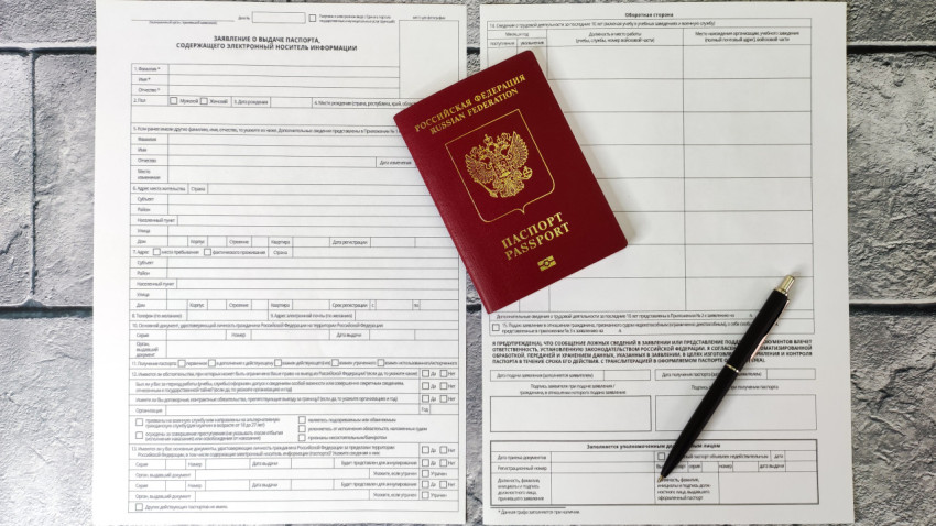 Загранпаспорт нового поколения на пустом бланке заявления и ручке на сером фоне