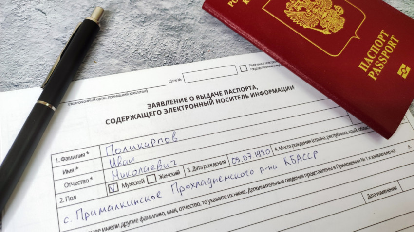Фрагмент заполнения заявления на загранпаспорт с паспортом и ручкой