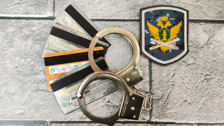 Наручники и банковские карты на фоне эмблемы ФССП