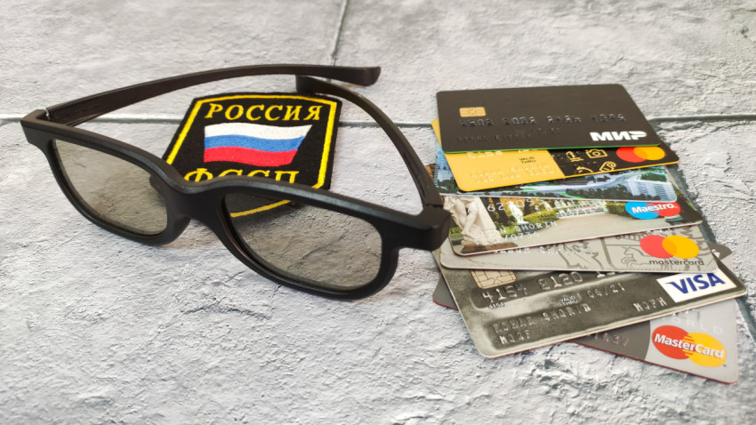 Очки и банковские карты на фоне шеврона ФССП